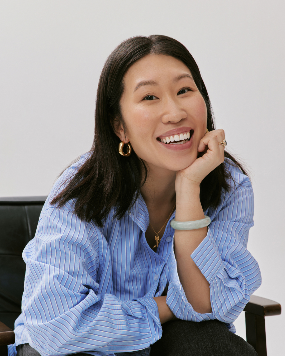 Founder wearing a blue striped shirt sitting on a black chair with a white background