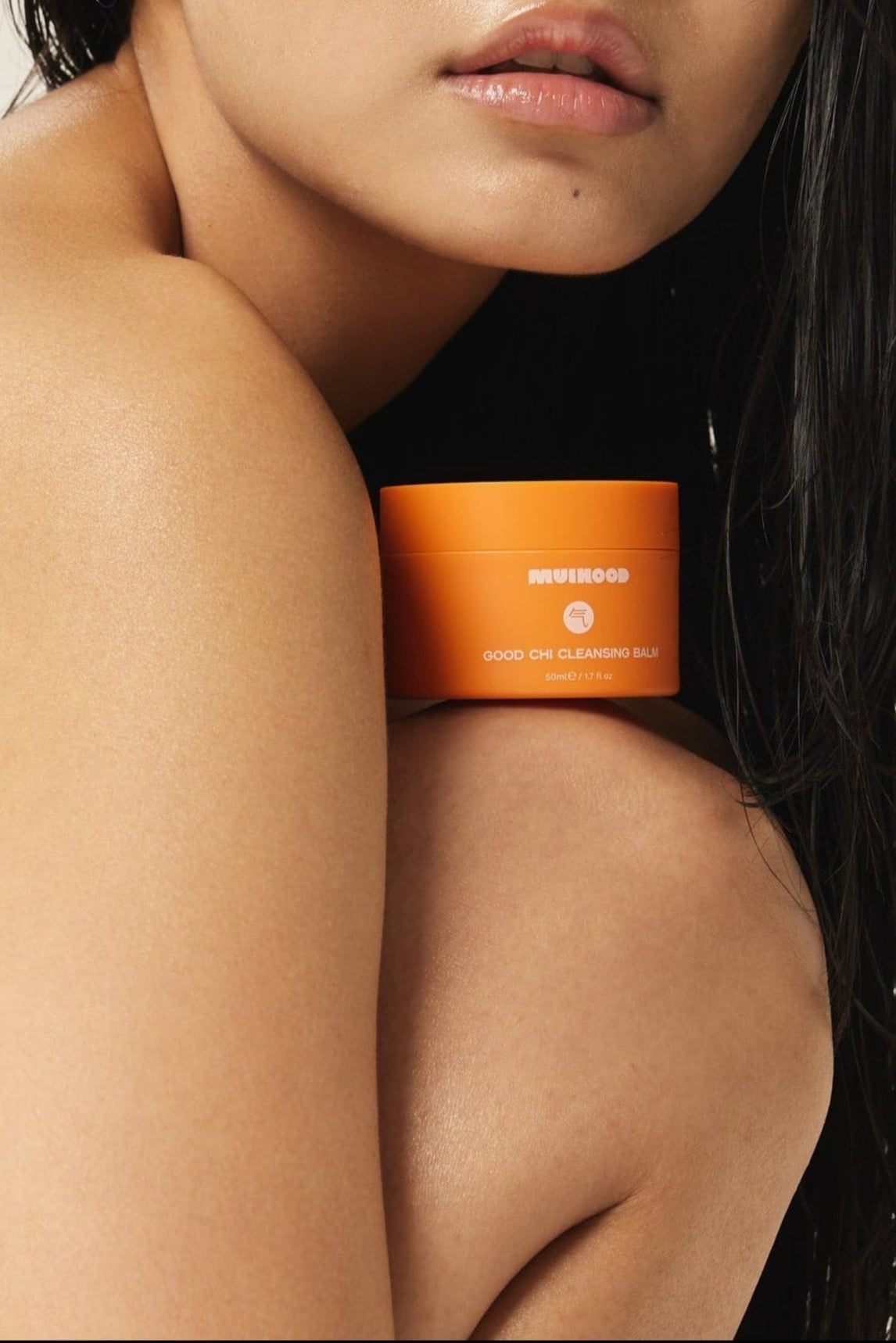 Woman with an Good Chi Cleanser on her shoulder against a neutral background